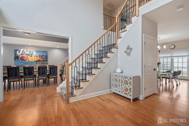 stairs featuring a high ceiling, wood finished floors, and a chandelier