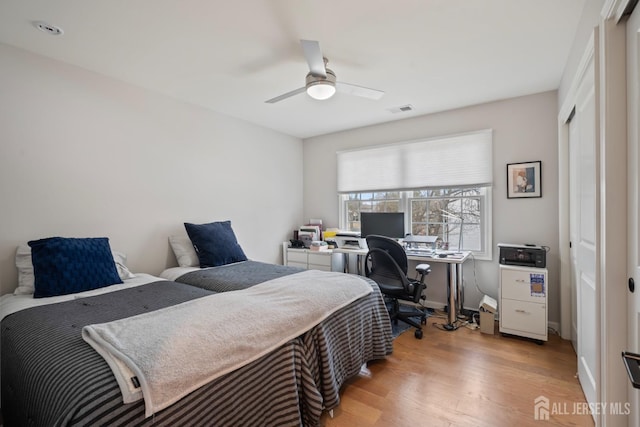 bedroom with baseboards, visible vents, light wood-style flooring, ceiling fan, and a closet