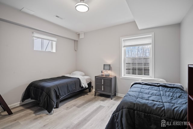 bedroom with baseboards, light wood-type flooring, multiple windows, and visible vents