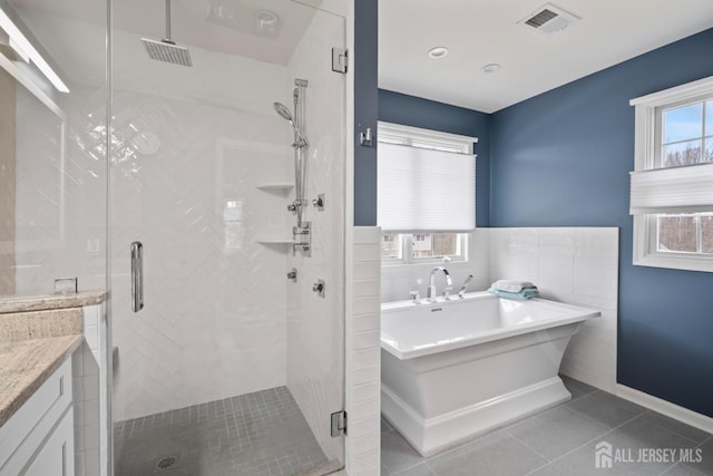 full bathroom featuring tile patterned floors, visible vents, a freestanding bath, and a stall shower