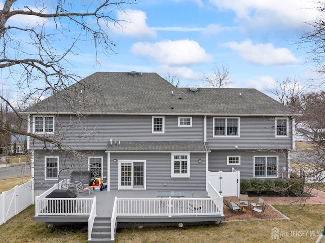 back of property with a gate, roof with shingles, a wooden deck, a yard, and a fenced backyard