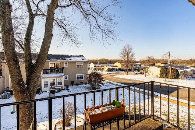 snow covered back of property featuring central AC