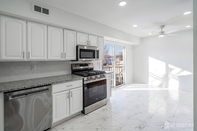 kitchen with white cabinetry, appliances with stainless steel finishes, stone counters, ceiling fan, and backsplash