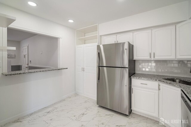 kitchen featuring white cabinetry, backsplash, light stone countertops, and appliances with stainless steel finishes