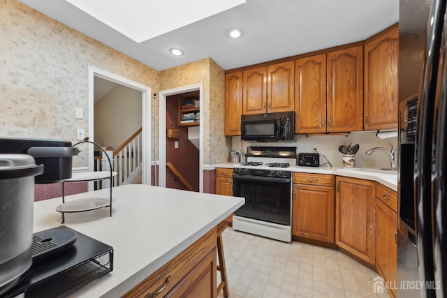 341 Ellis Pkwy, Piscataway, NJ 08854 - kitchen featuring black appliances, wallpapered walls, a sink, brown cabinets, and light countertops