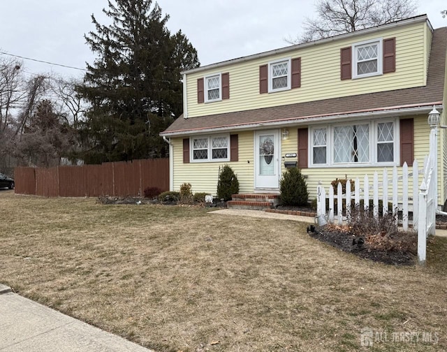 view of front of home featuring entry steps, a front lawn, and fence