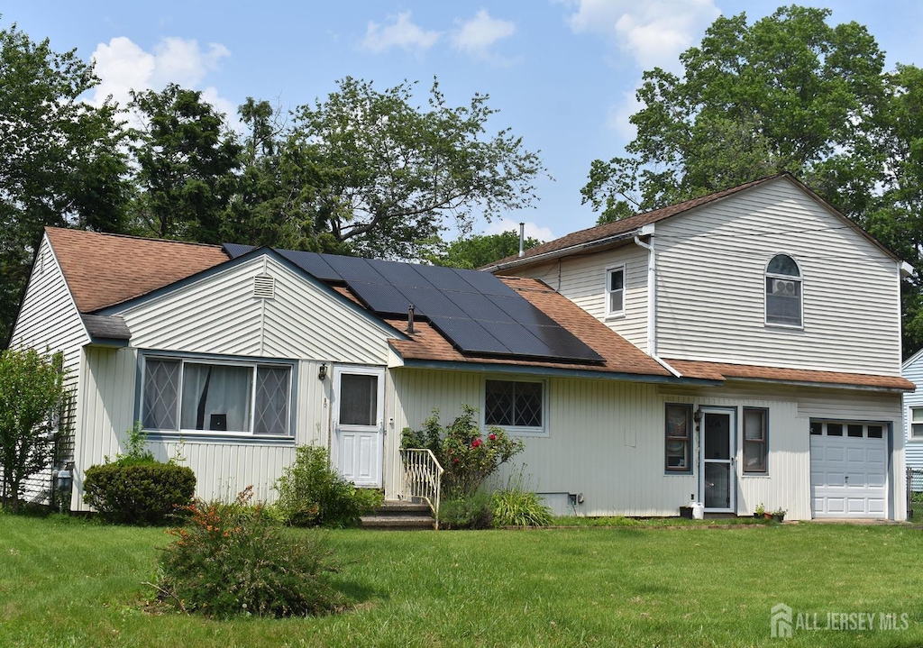 126 Lakeside Dr, Piscataway, NJ 08854 - back of house featuring solar panels, a yard, an attached garage, and a shingled roof