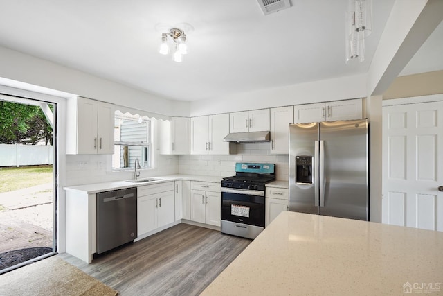 431-431 Garfield Ave, South Plainfield, NJ 07080 - kitchen featuring appliances with stainless steel finishes, under cabinet range hood, decorative backsplash, white cabinets, and wood finished floors