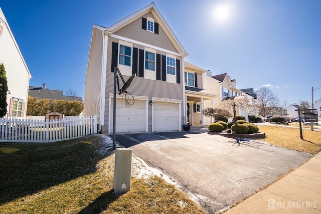 traditional-style house with a garage, a residential view, aphalt driveway, fence, and a front yard