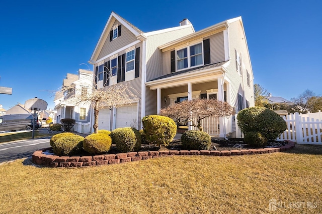 view of front of home featuring an attached garage, a chimney, fence, and a front yard