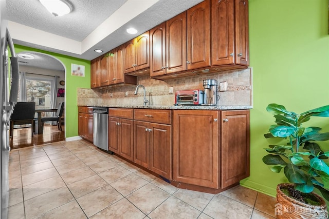 kitchen with light tile patterned floors, decorative backsplash, a sink, and dishwasher