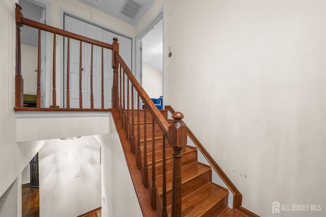 staircase featuring attic access, visible vents, and wood finished floors