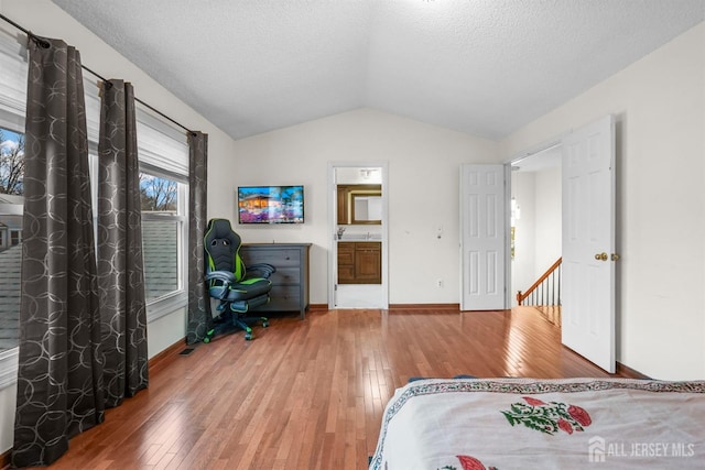 bedroom with lofted ceiling, baseboards, a textured ceiling, and hardwood / wood-style floors