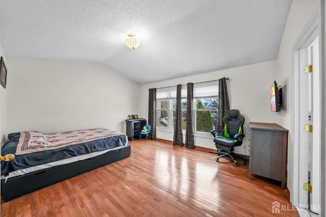 bedroom featuring lofted ceiling, a textured ceiling, and hardwood / wood-style flooring