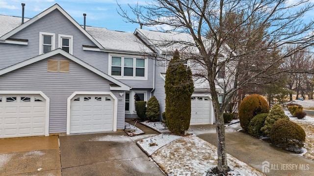 multi unit property with an attached garage, a shingled roof, and concrete driveway