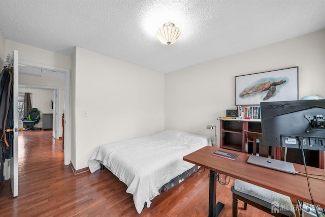 bedroom featuring a textured ceiling, baseboards, and wood finished floors