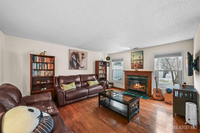 living room with a textured ceiling, hardwood / wood-style floors, and a fireplace with flush hearth