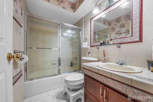 bathroom with tile walls, bath / shower combo with glass door, backsplash, vanity, and tile patterned flooring