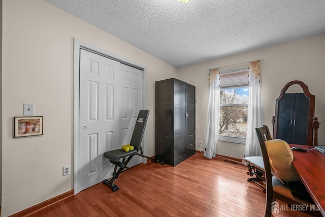 office space with light wood-style floors, visible vents, a textured ceiling, and baseboards