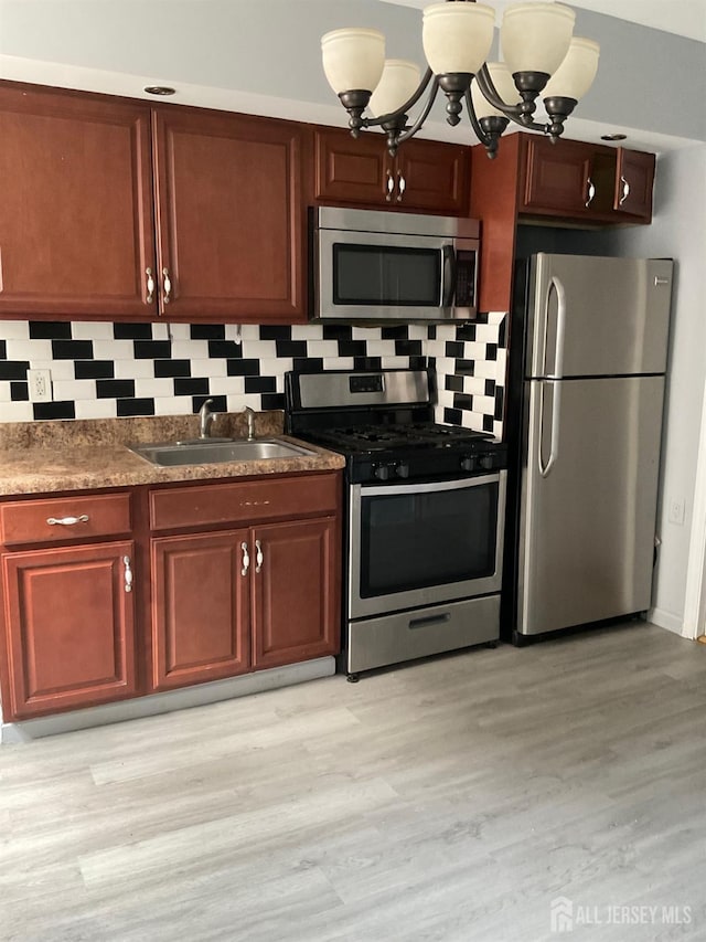 79 W 18th St, Bayonne, NJ 07002 - kitchen with appliances with stainless steel finishes, backsplash, light wood finished floors, a chandelier, and dark countertops