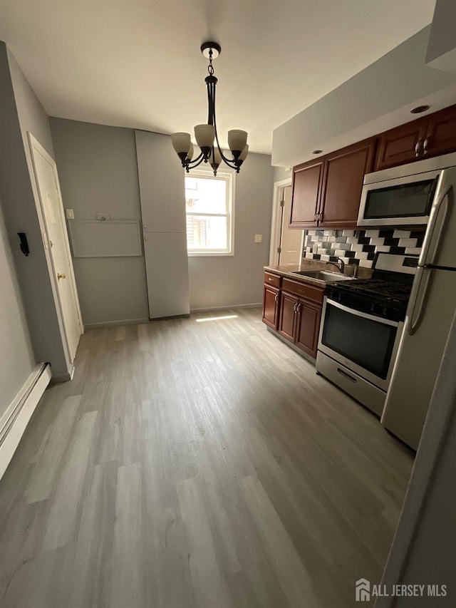 79 W 18th St, Bayonne, NJ 07002 - kitchen with stainless steel appliances, decorative backsplash, light wood-style flooring, a chandelier, and pendant lighting