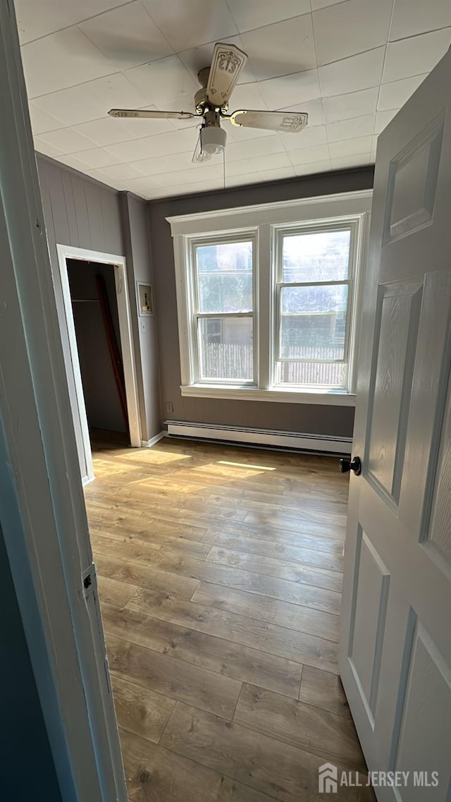 79 W 18th St, Bayonne, NJ 07002 - spare room featuring baseboard heating, hardwood / wood-style floors, and a ceiling fan