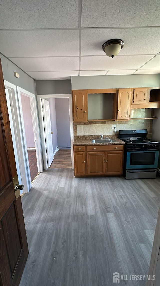 79 W 18th St, Bayonne, NJ 07002 - kitchen with black gas stove, wood finished floors, decorative backsplash, and a paneled ceiling