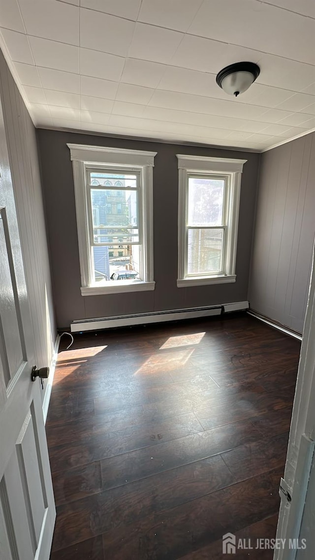 79 W 18th St, Bayonne, NJ 07002 - spare room featuring healthy amount of natural light, a baseboard heating unit, and dark wood-type flooring