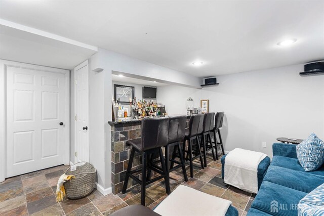 bar with a bar, recessed lighting, baseboards, and stone tile flooring