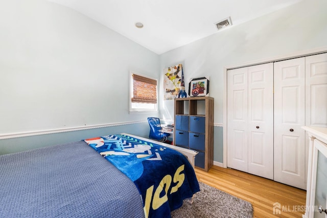 bedroom with a closet, lofted ceiling, light wood-style flooring, and visible vents