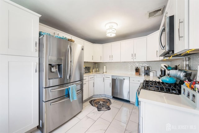 kitchen featuring light countertops, marble finish floor, stainless steel appliances, backsplash, and visible vents