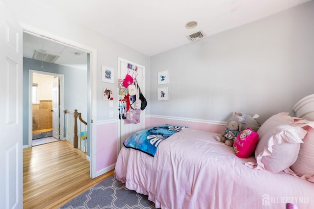 bedroom featuring visible vents, attic access, and wood finished floors