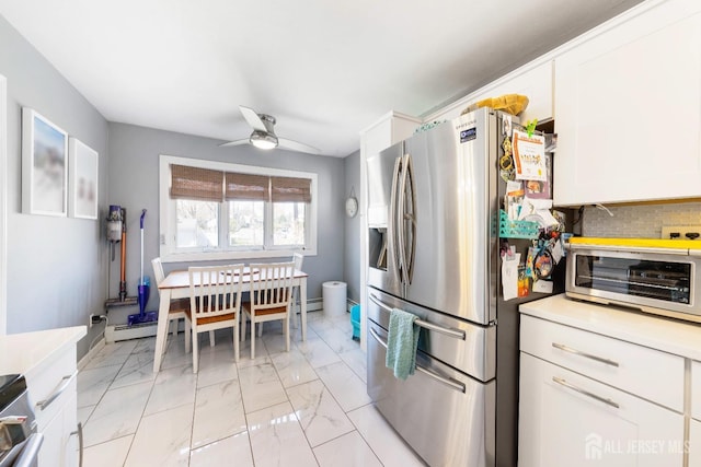 kitchen with marble finish floor, ceiling fan, light countertops, white cabinetry, and stainless steel fridge with ice dispenser
