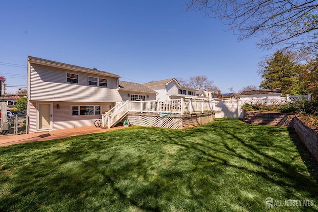 rear view of property with a lawn, a deck, stairway, and a fenced backyard