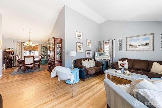 living room featuring high vaulted ceiling, light wood-type flooring, and a chandelier