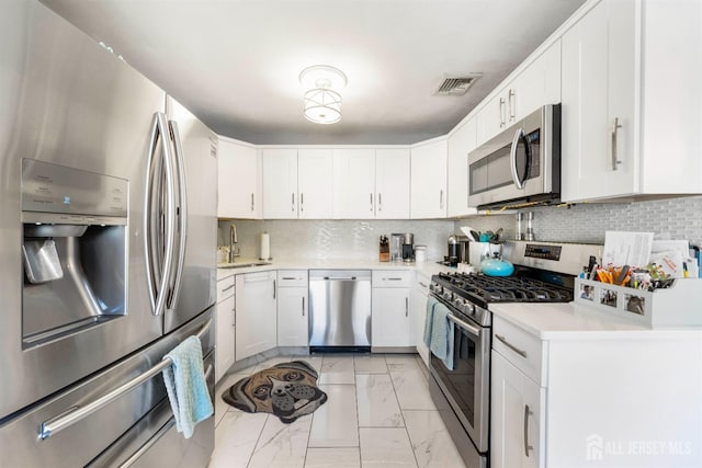 kitchen featuring appliances with stainless steel finishes, a sink, light countertops, marble finish floor, and visible vents