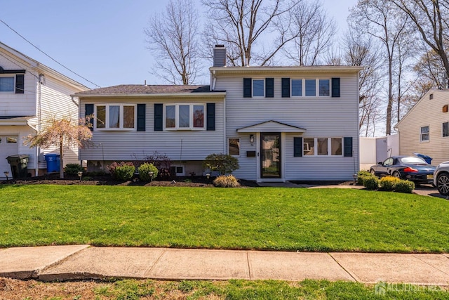 split level home with a chimney and a front yard