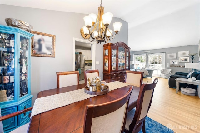 dining room with wood finished floors, lofted ceiling, and an inviting chandelier