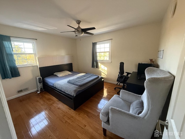 bedroom featuring ceiling fan, hardwood / wood-style floors, and multiple windows