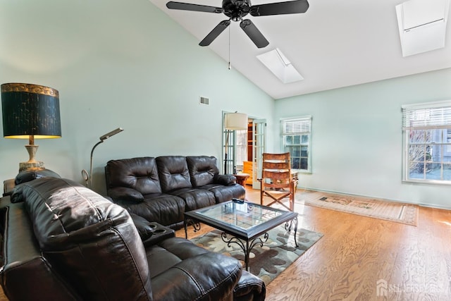 living area featuring a skylight, plenty of natural light, visible vents, and wood finished floors