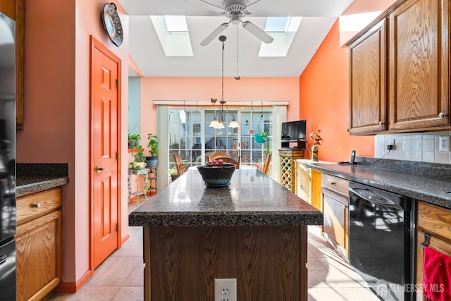 kitchen featuring light tile patterned flooring, a skylight, black dishwasher, decorative backsplash, and dark countertops