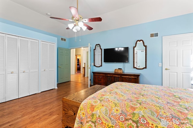 bedroom featuring two closets, wood finished floors, and visible vents