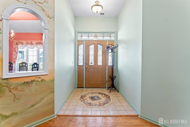 foyer with arched walkways, baseboards, visible vents, and tile patterned floors