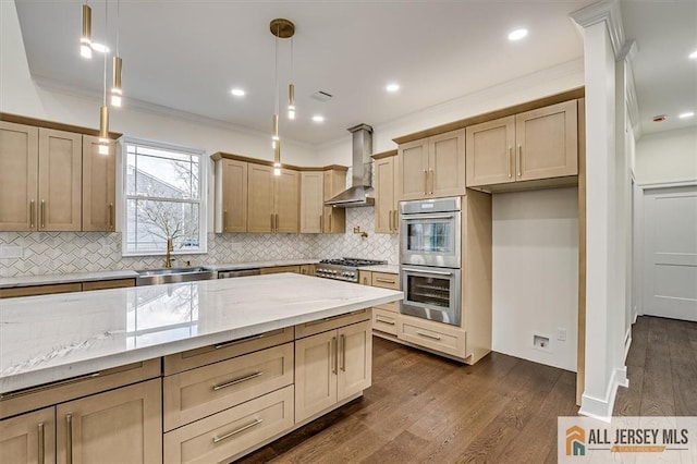 kitchen with sink, pendant lighting, wall chimney range hood, stainless steel appliances, and light stone countertops