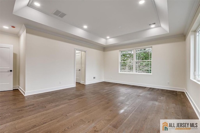 unfurnished room featuring a tray ceiling, dark wood-type flooring, and crown molding