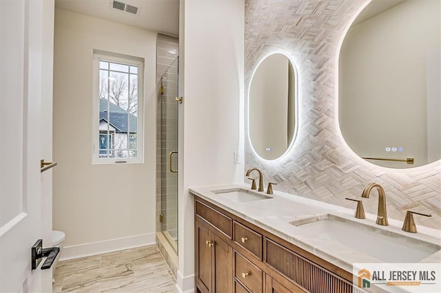 bathroom with vanity, tasteful backsplash, and a shower with door