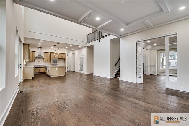 unfurnished living room with coffered ceiling, dark wood-type flooring, sink, and beam ceiling