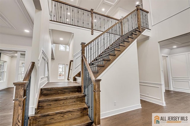 staircase with hardwood / wood-style flooring and a towering ceiling