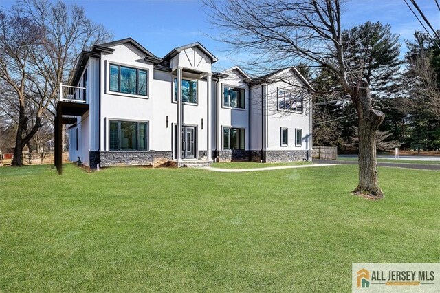 view of front of home with a balcony and a front yard