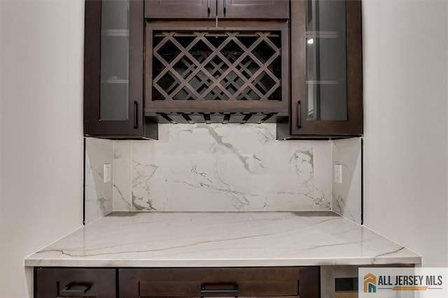 interior space with dark brown cabinets, backsplash, and light stone counters